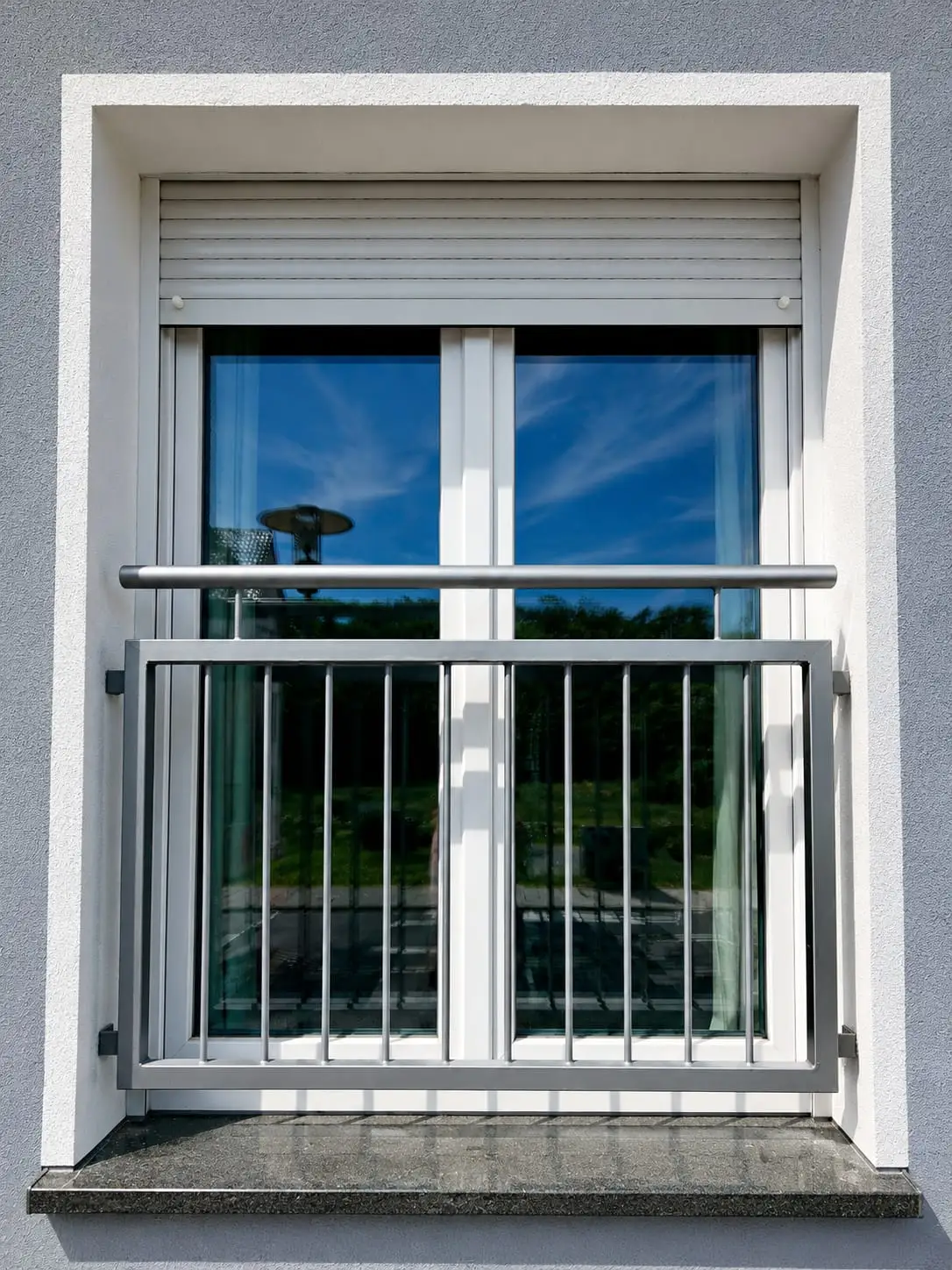 Französischer Balkon aus Edelstahl mit waagerechten Stäben vor einem bodentiefen Fenster