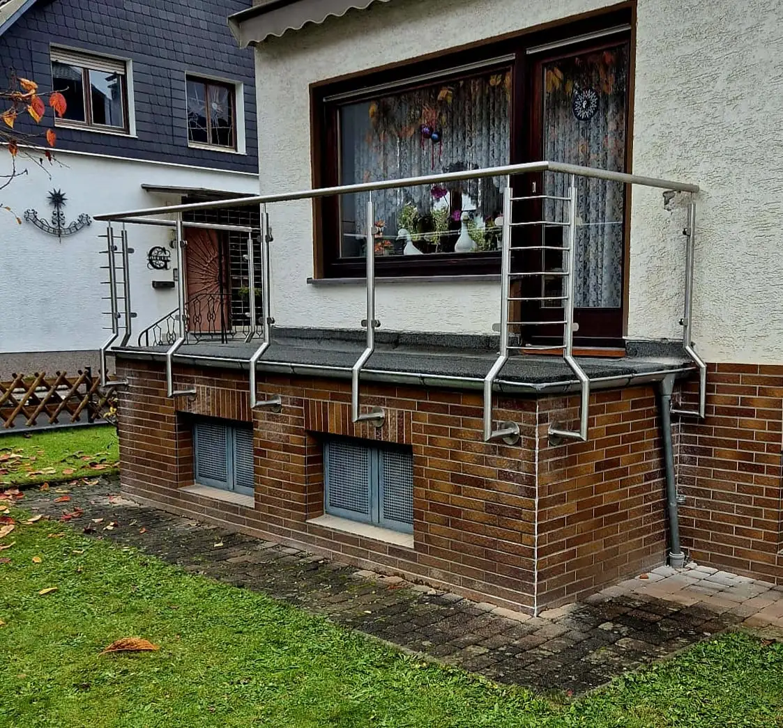 Terrassengeländer aus Edelstahl mit Querseilen vor einem Garten