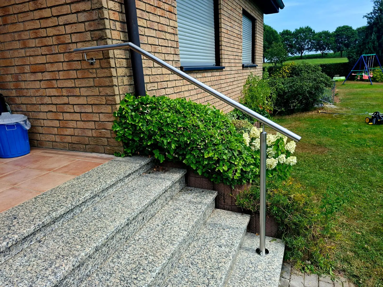 Edelstahl-Handlauf entlang einer Klinkerwand an einer Außentreppe