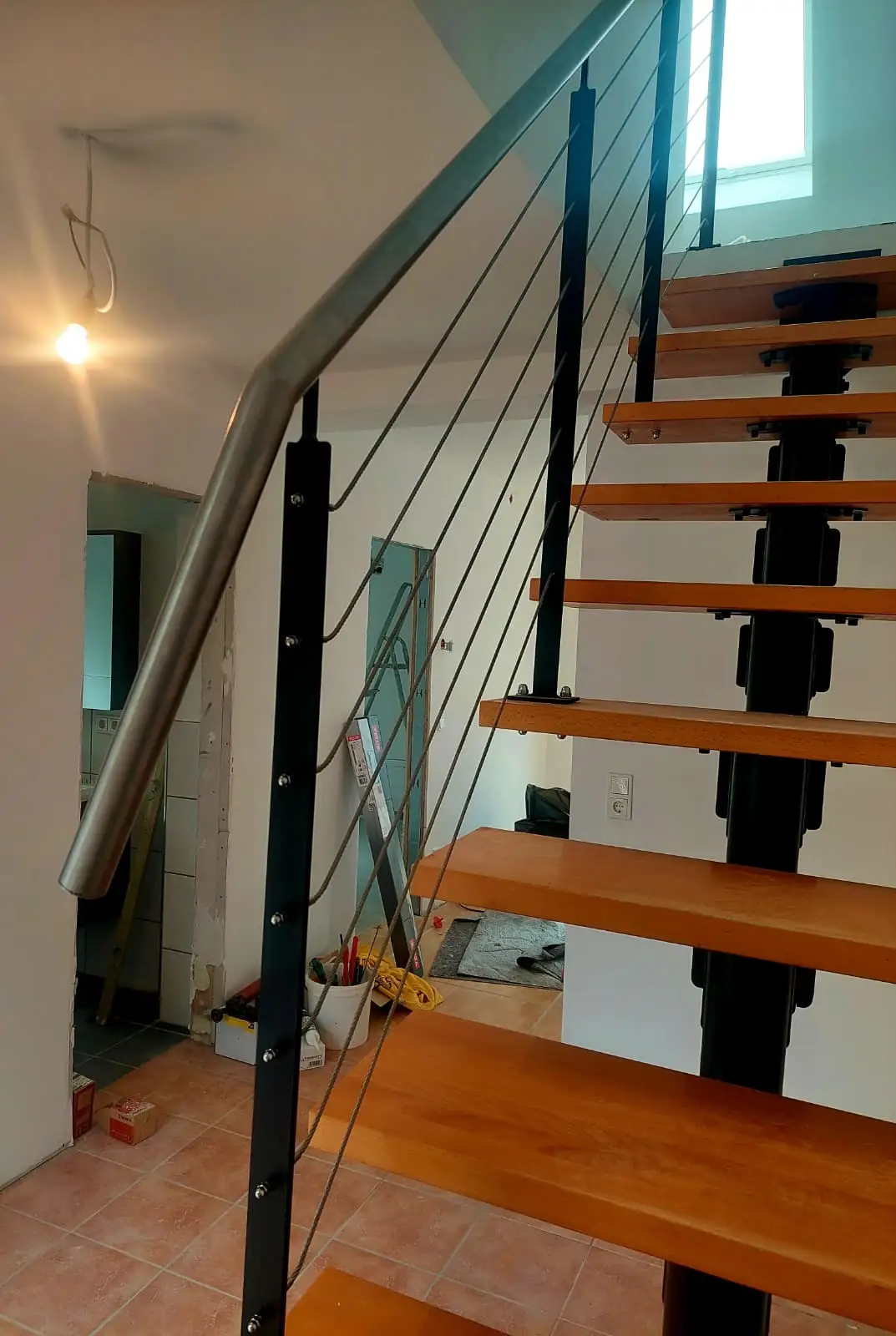 Innentreppe mit dunkler Stahlwange und hellen Holzstufen in einem Wohnhaus