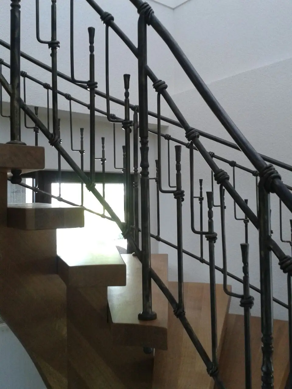 Schmiedeeisernes Treppengeländer mit verzierten Stäben in einem Treppenhaus