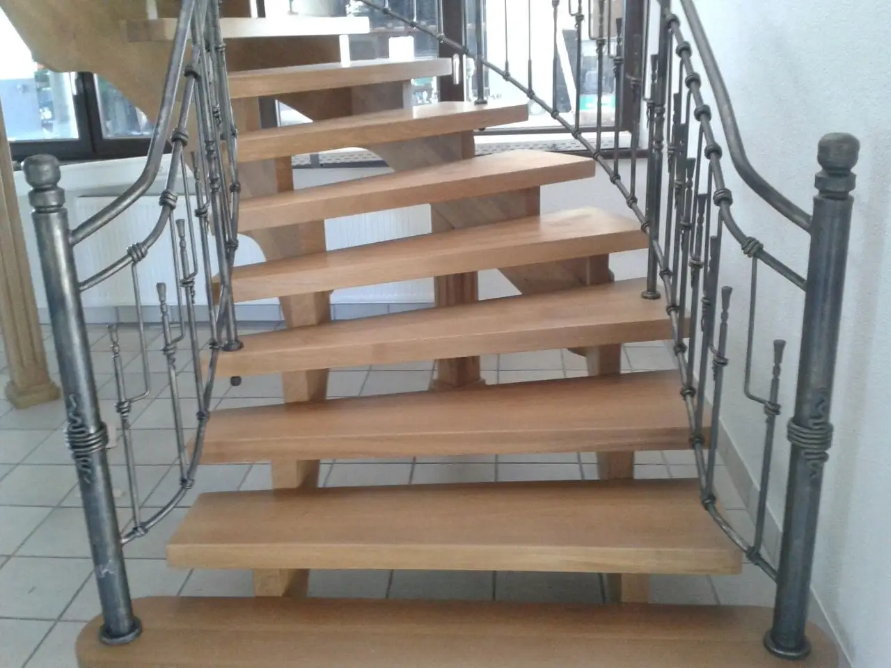 Treppe mit Holzstufen und verziertem Schmiedegeländer im Treppenhaus